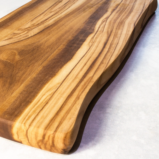 Close-up of handcrafted olive wood cutting board showing rich natural grain and smooth live edge design.