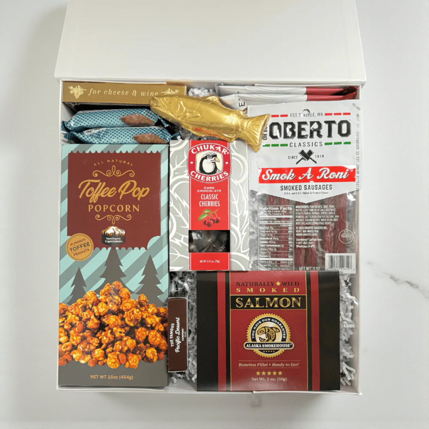snack box filled with snacks made in WA. The gift box includes: smoked salmon, pepperoni sticks, raosted nuts, crackers chocolate cherries and a solid chocolate salmon
