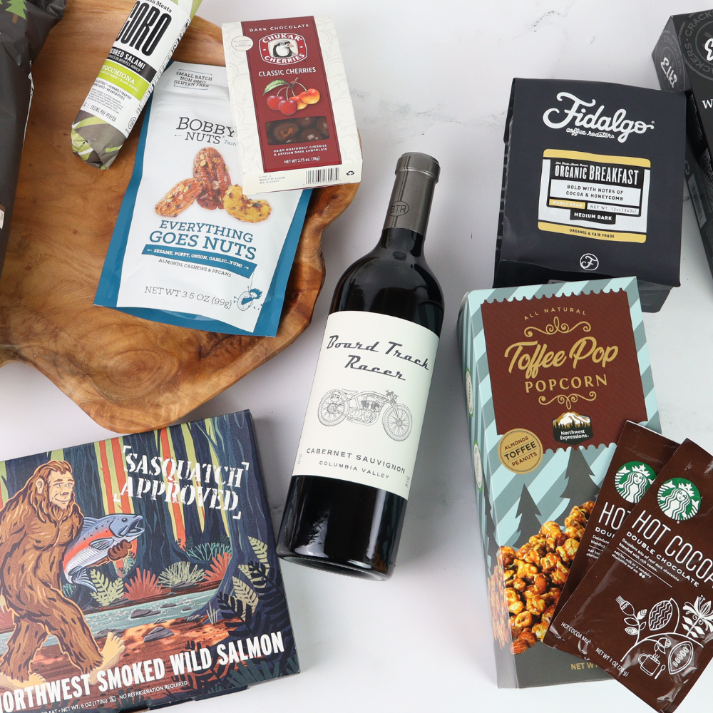 Assorted made in washington products including a bottle of wine, snacks, and packaged goods on a white surface.
