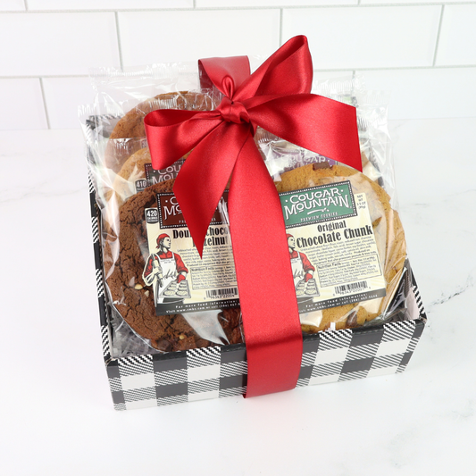 Packaged cookies with a red ribbon on a white tiled background. Giant Cougar Mountain Cookies are 5 inches in diameter and are the size of your hand. The weigh a whopping 3.5oz. equal to almost 4 regular cookies