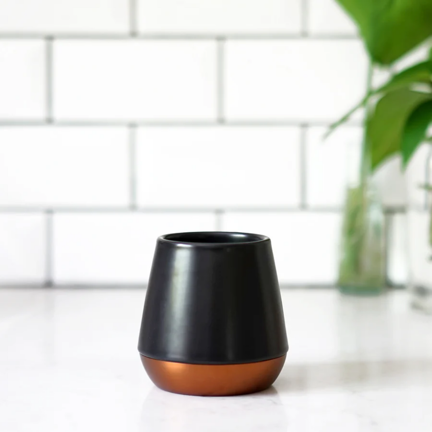 Black and copper fellow joey mug on a white surface with a tiled wall background