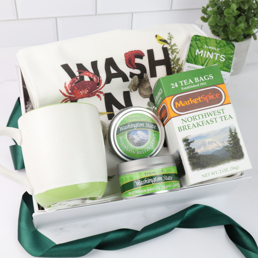 Northwest-themed gift box with a green teacup, MarketSpice tea, soy candle, Seattle Chocolate mint bar, churro cookies, and mints. Ideal for cozying up or gifting a taste of the Pacific Northwest.