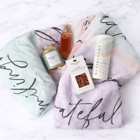 Gift set with tea, honey, and cookies on a decorative blanket with cursive text.