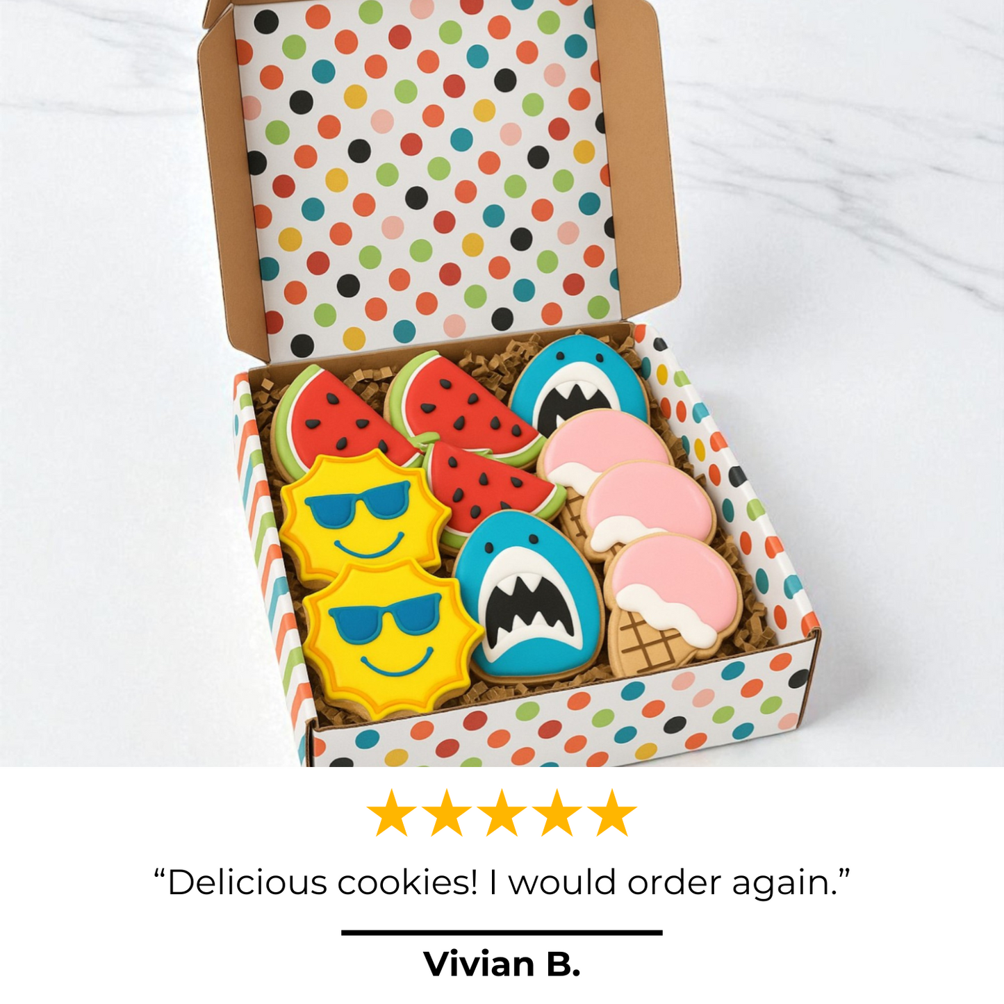 Box of colorful cookies with shark and sun designs on a polka dot background.