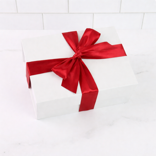 White gift box with a large red ribbon on a white tiled background