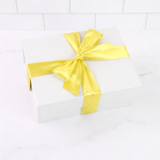 White box with a yellow ribbon on a white tiled background