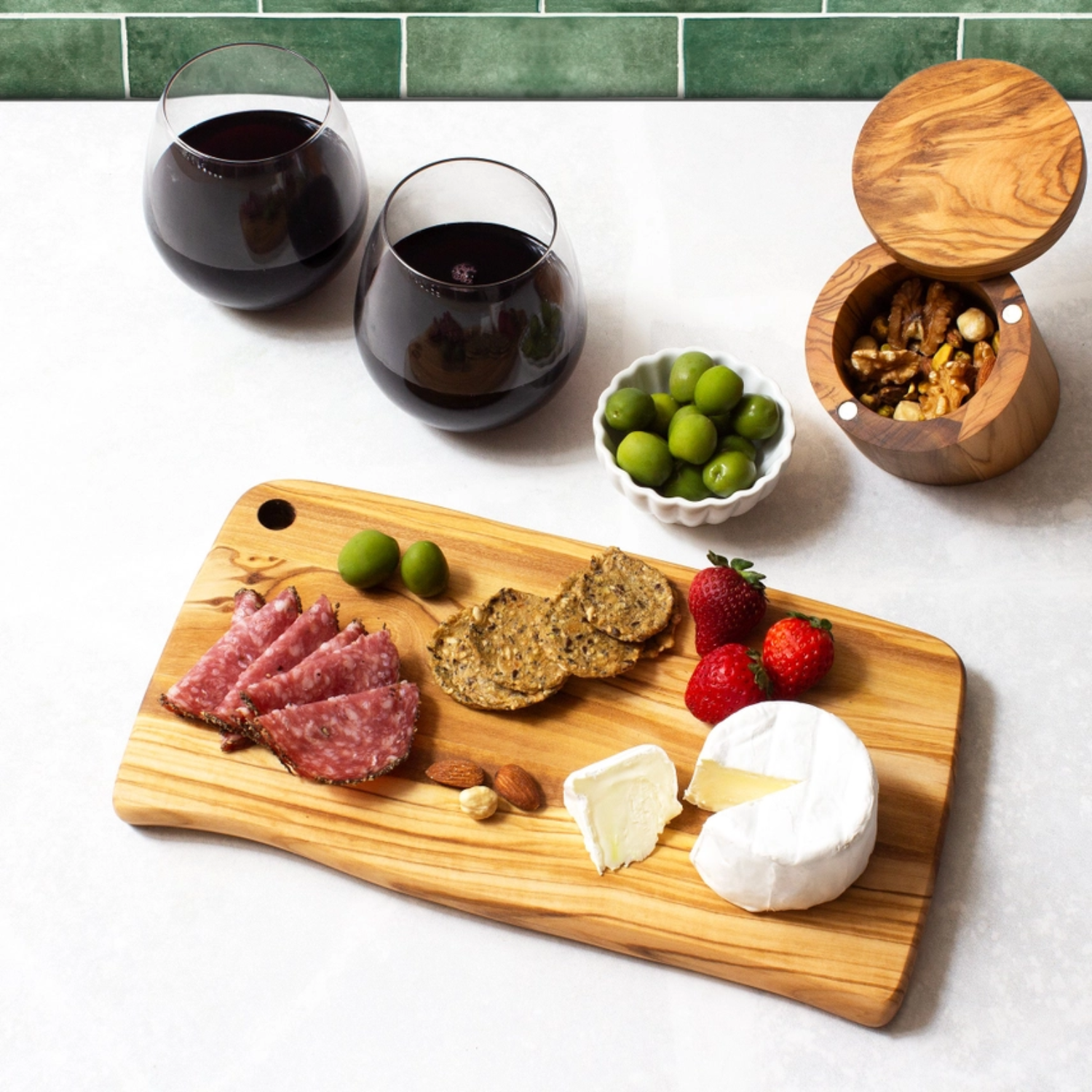 Olive wood charcuterie board arranged with cheese, meats, and olives, rustic serving board for entertaining and gifts.