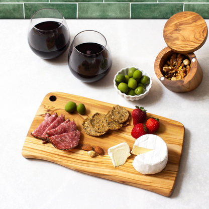 Olive wood charcuterie board arranged with cheese, meats, and olives, rustic serving board for entertaining and gifts.