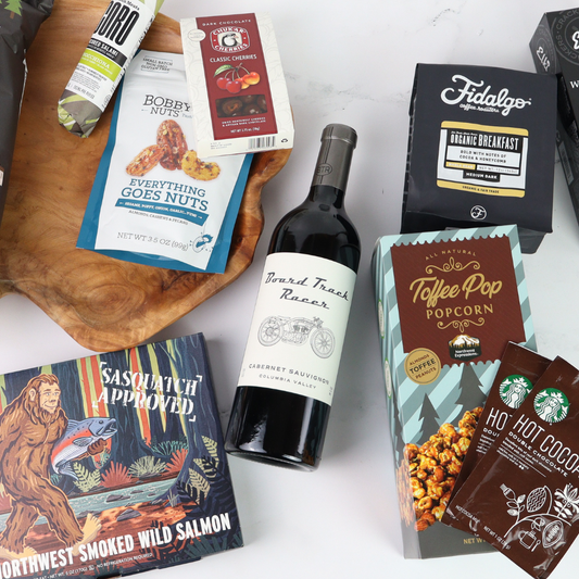 Assorted made in washington products including a bottle of wine, snacks, and packaged goods on a white surface.