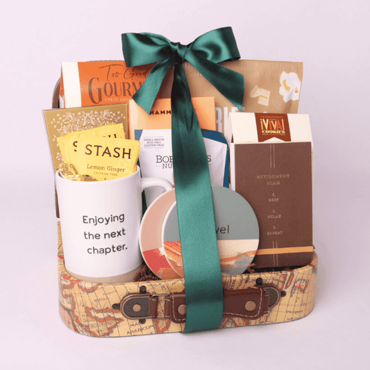 Retirement gift basket with travel themed goodies.  Basket includes travel snacks, retirement mug, stone coasters, and notebook all assembled in a decorative mini suitcase.