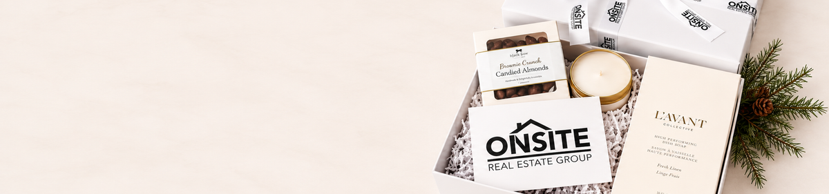 A curated gift box set from Onsite Real Estate Group, featuring a white candle, a small boxed item, and a card, arranged in a white box with shredded paper on a light beige background.