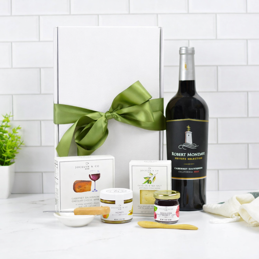 Cabernet Sauvignon gourmet gift box with crackers, cheese spread, honey and preserves in gold ribbon packaging