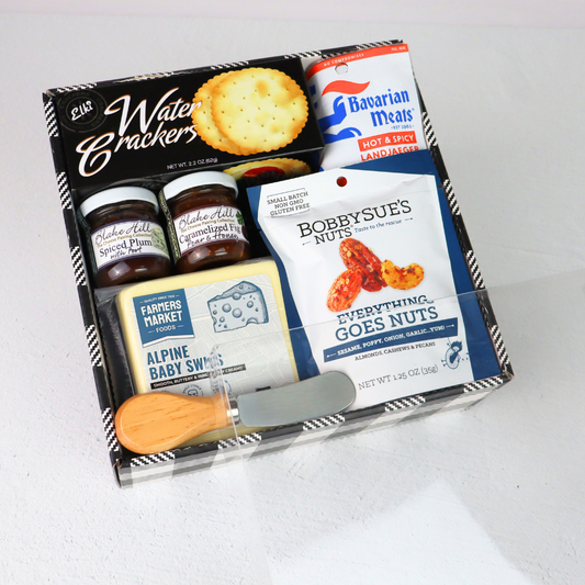 Assorted food items including crackers, meats, and nuts made in Washington in a box on a white background