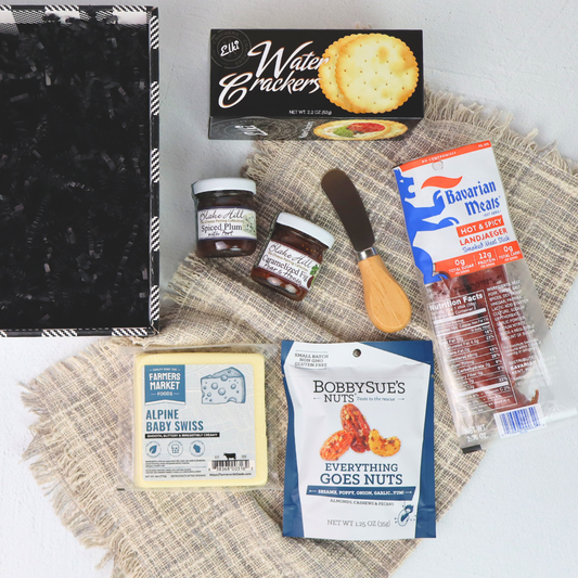 Assorted pacific northwest food items including crackers, meats, and cheese on a textured surface.