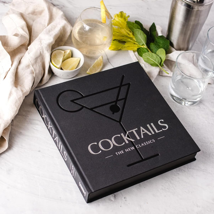 Cocktails book with cocktail-making ingredients on a table
