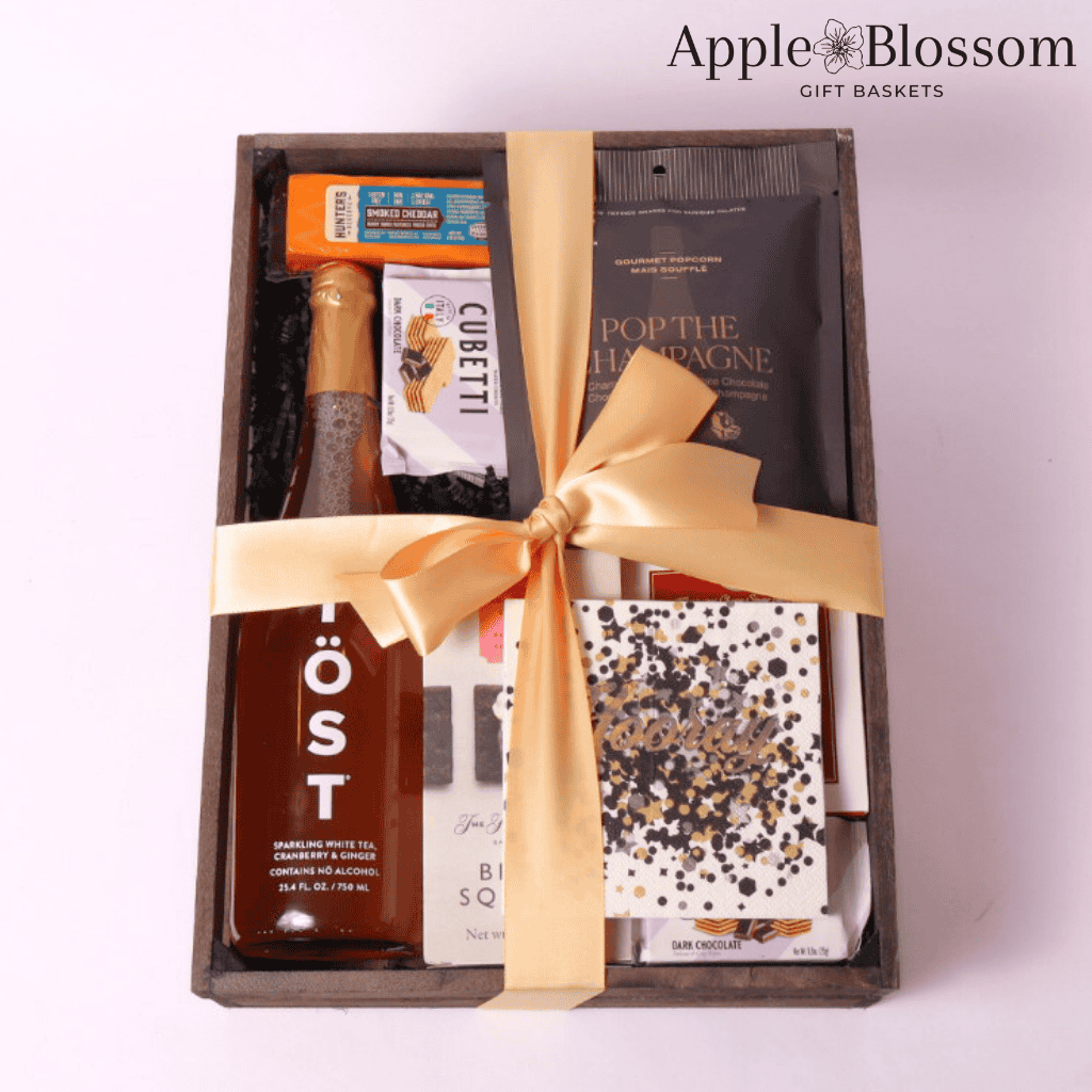 cue the confetti celebration gift basket comes in a wooden tray with cheese, crackers, white tea, wafer cookies, nuts, party popper, napkins and champagne infused white chocolate popcorn.  Made by Apple Blossom Gift Baskets