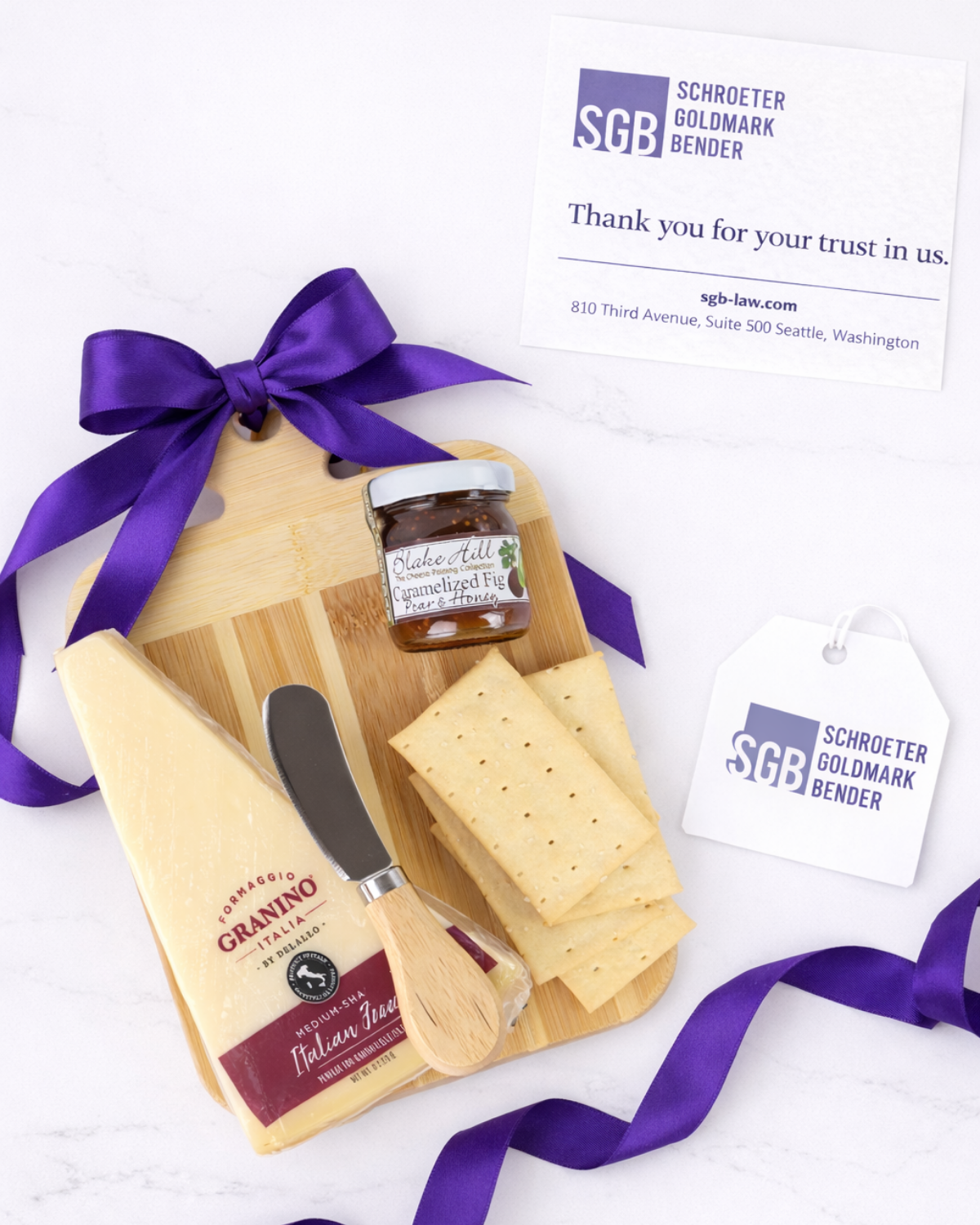 Custom logo gift tag attached to purple ribbon on artisan cheese board corporate gift