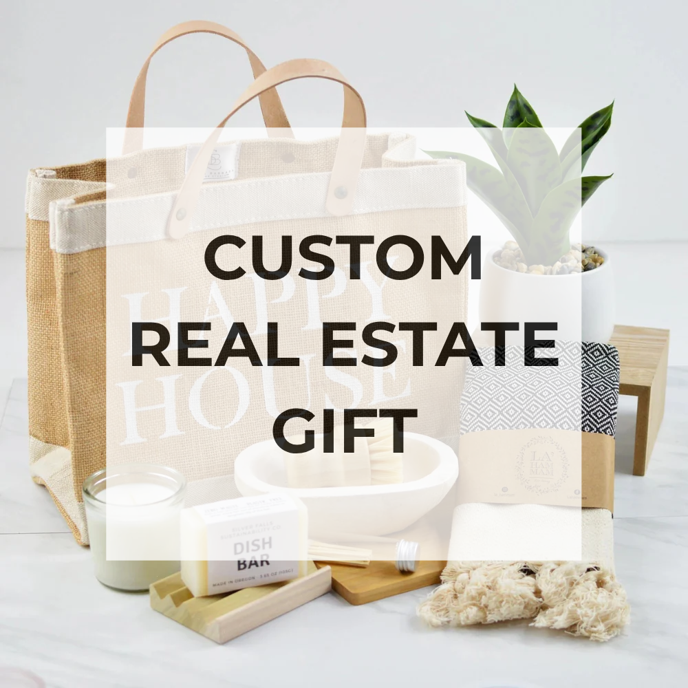 Custom real estate gift set with tote bag, candle, and other items on a white surface.