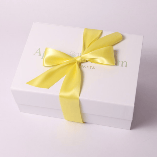 Image of the signature white gift box elegantly wrapped with a yellow satin bow, creating a bright and cheerful presentation for a housewarming gift, self-care gift box, or corporate gift. Perfect for thinking of you, get well soon, or tea lover gifts.