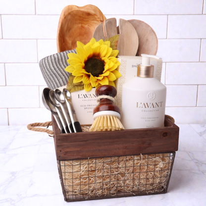 For the Kitchen Gift Basket – A beautifully curated kitchen gift basket featuring L’AVANT dish soap, eco-friendly sponges, a salad serving set, a hand-carved wooden platter, and more, elegantly arranged in a rustic wire and wood basket. Seattle housewarming  gift baskets