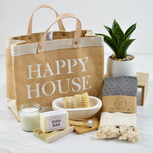 Happy House gift set with jute tote, candle, soap, hand towel, wooden tray, and faux plant arranged for housewarming gift