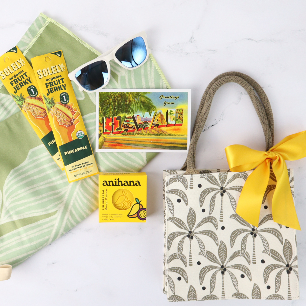 Tote bag with palm leaf pattern, yellow ribbon, and tropical-themed items on a white background