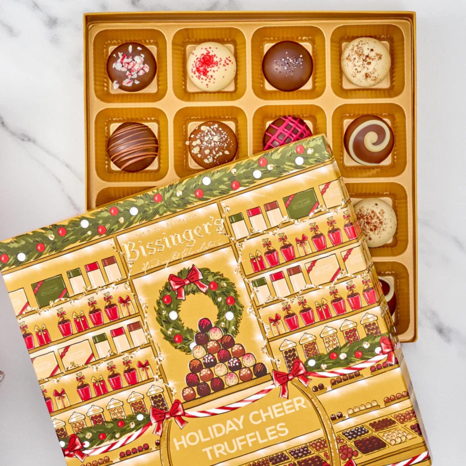 Assorted holiday truffles in Peppermint, Eggnog, and Gingerbread flavors arranged on a gold tray with holiday décor.
