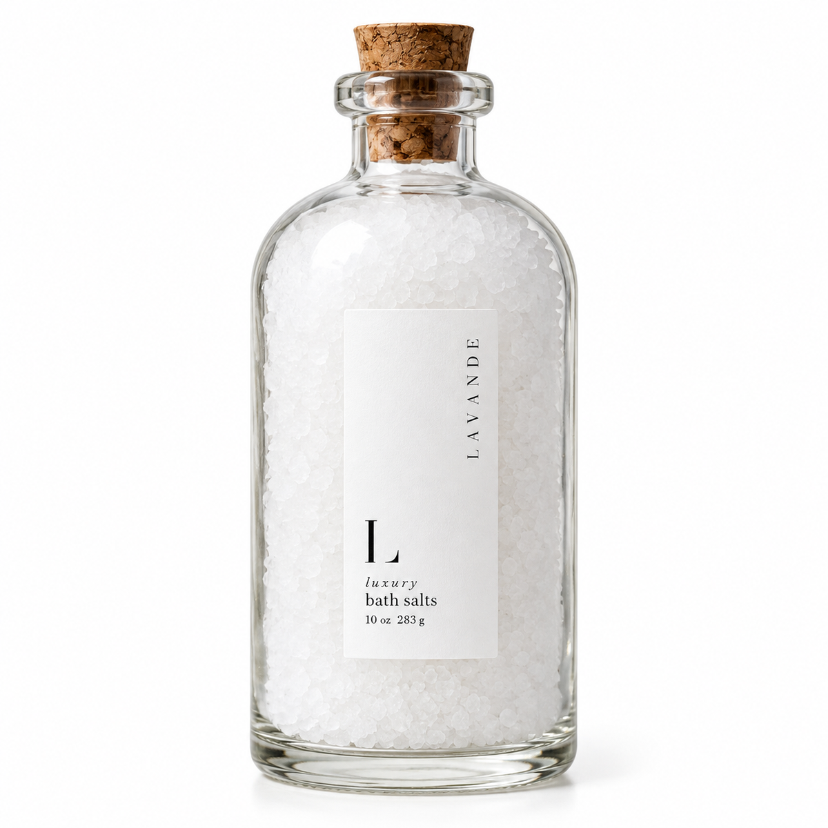 A clear glass bottle filled with white bath salts and sealed with a natural cork stopper, featuring a minimalist white label that reads 'LAVANDE' and 'luxury bath salts 10 oz 283 g'.