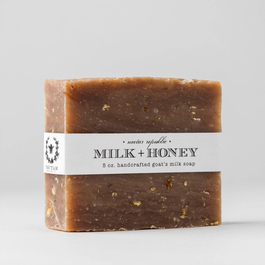 Bar of soap labeled 'Milk + Honey' on a gray background