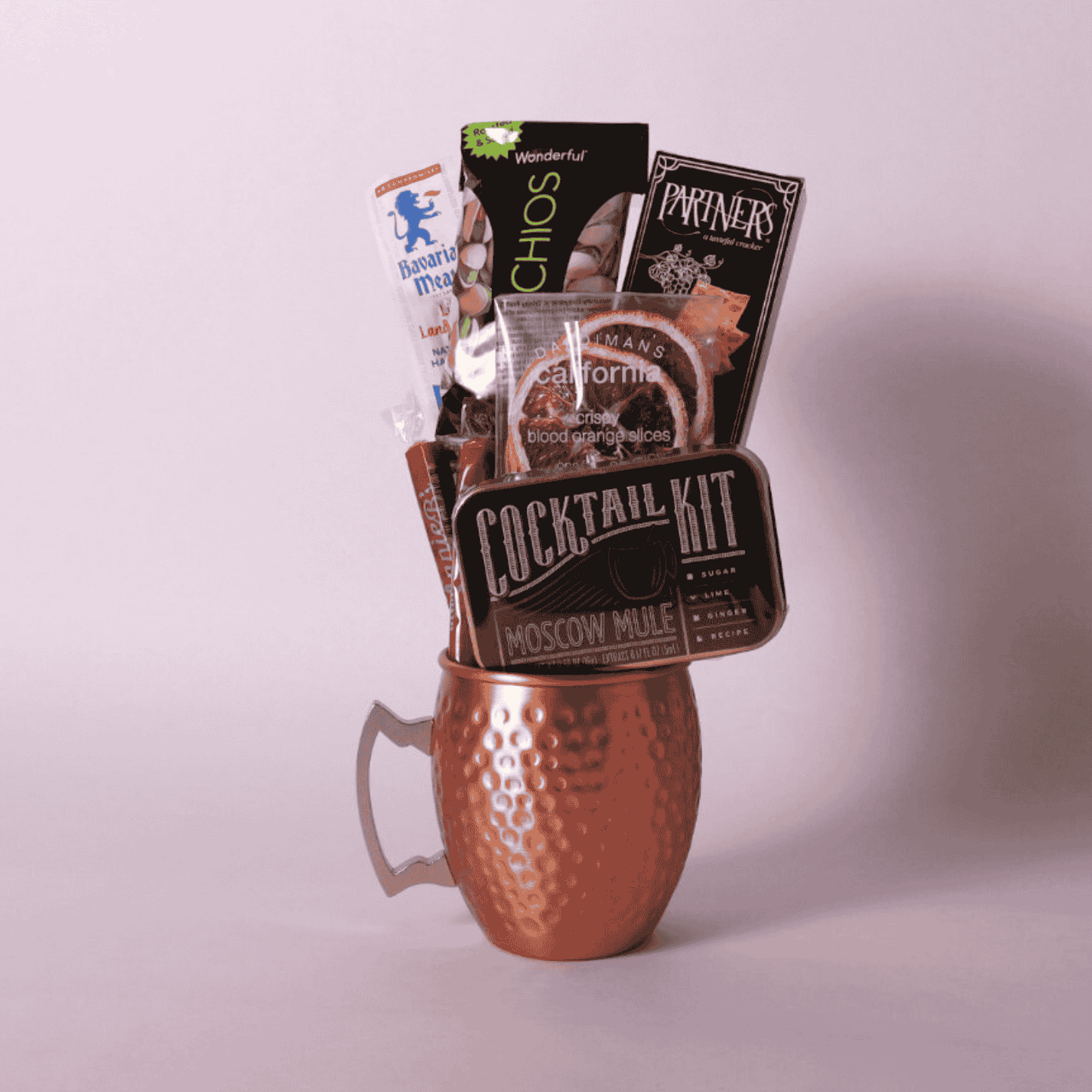 single Moscow mule mug gift basket includes a cocktail kit, two caramels, dried orange slices, crackers, pistachios and beef stick.