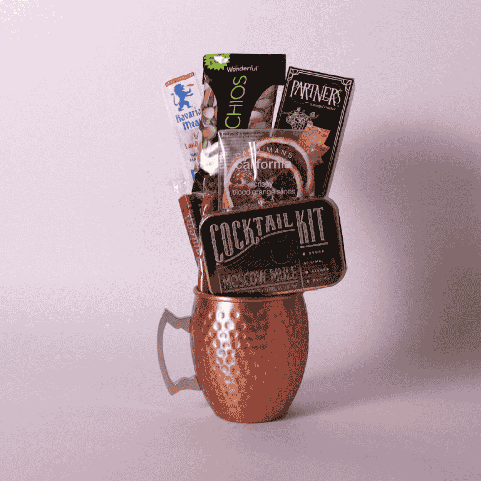single Moscow mule mug gift basket includes a cocktail kit, two caramels, dried orange slices, crackers, pistachios and beef stick.