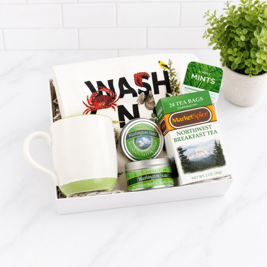 Northwest-themed gift box with a green teacup, MarketSpice tea, soy candle, Seattle Chocolate mint bar, churro cookies, and mints. Ideal for cozying up or gifting a taste of the Pacific Northwest.