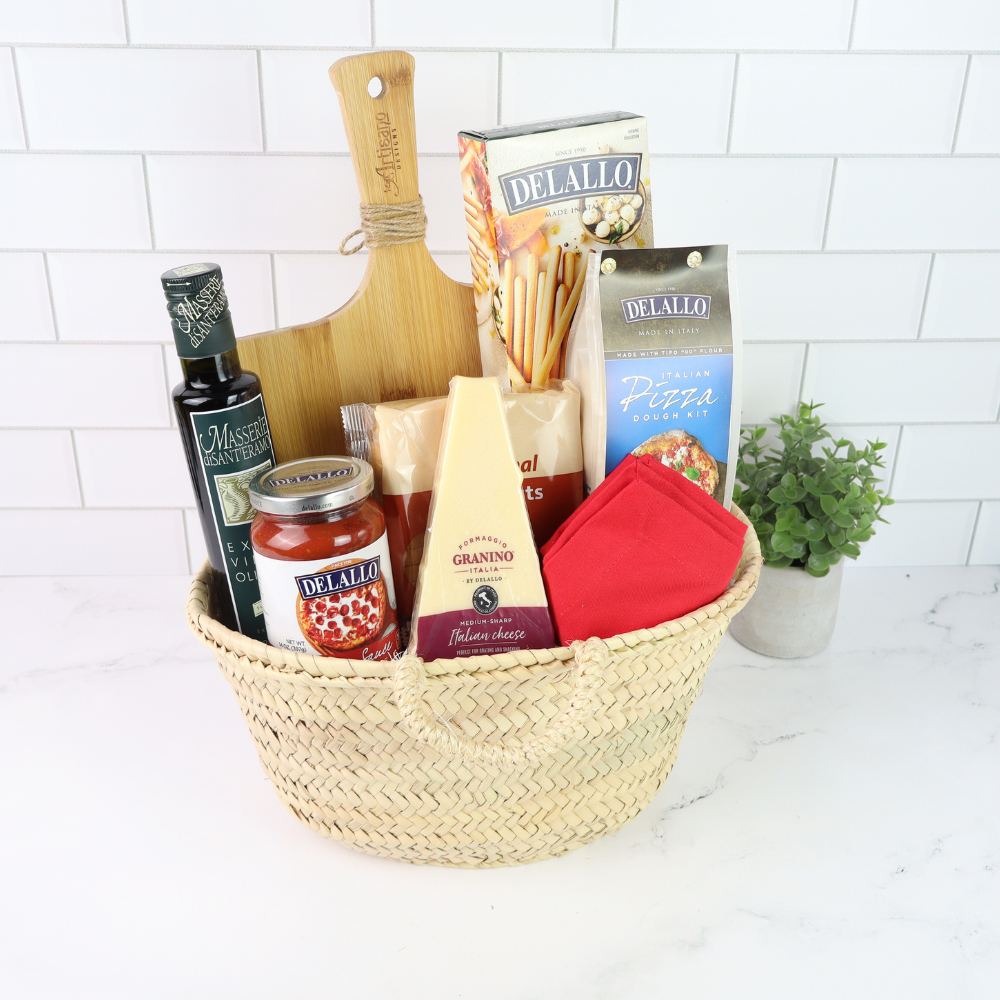 Basket of Italian food items including cheese, sauce, and bread on a kitchen counter.
