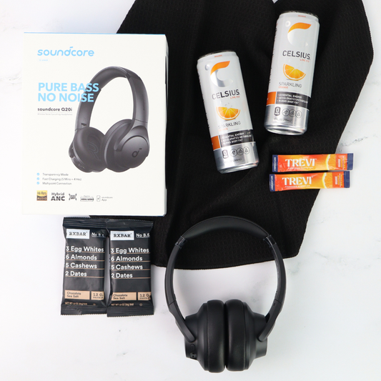 Flat lay of The Recharge gift box with headphones, body care items, and snack treats