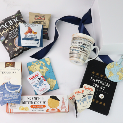 retirement Gift box with travel-themed items including a retired mug, passport cover, luggage tag, book, cookies, and books on a white background