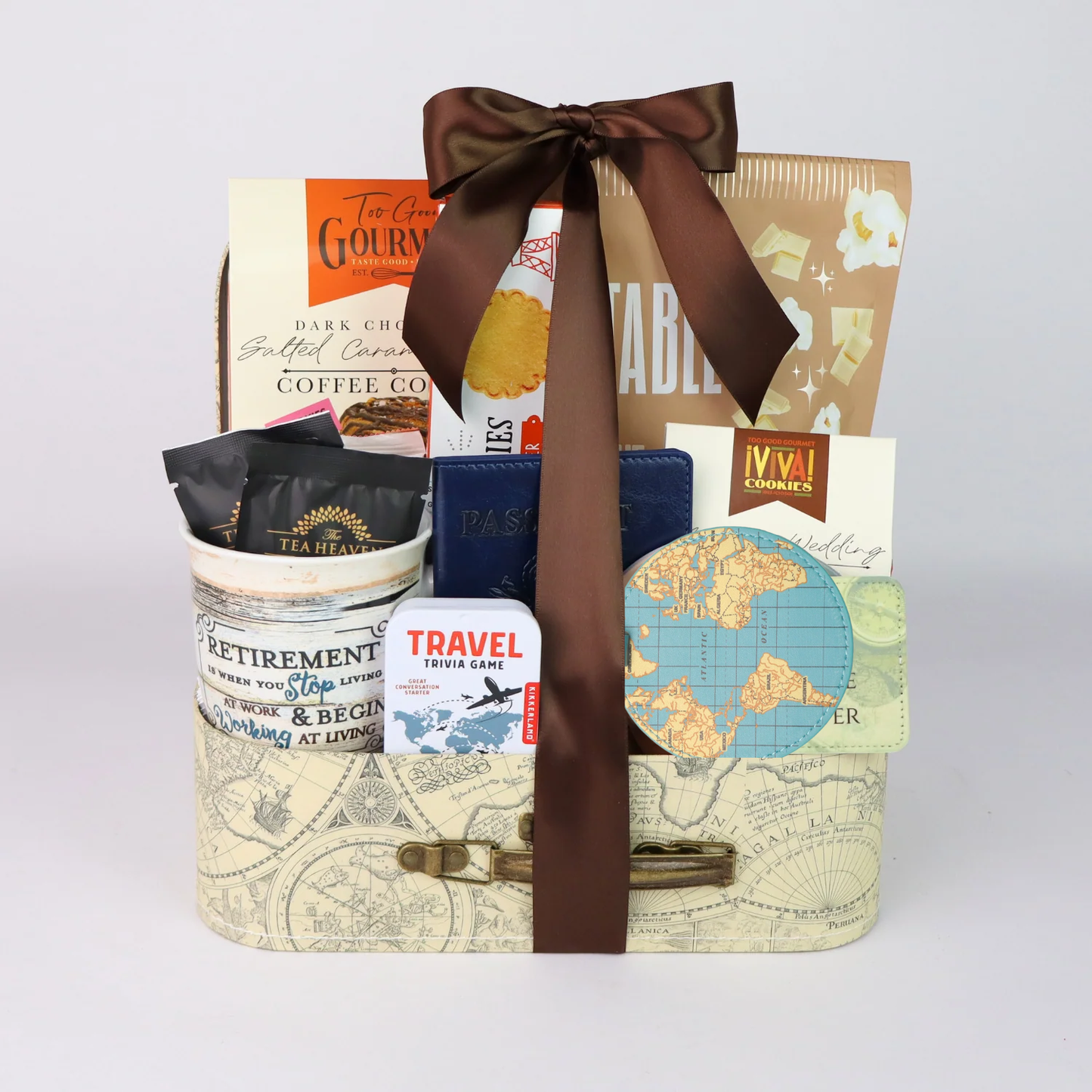 Retirement gift basket with travel themed goodies.  Basket includes travel snacks, retirement mug, stone coasters, and notebook all assembled in a decorative mini suitcase.
