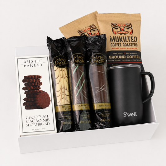 A curated gift box containing a box of Rustic Bakery chocolate cacao nib shortbread, three packages of Delia's Chocolate treats, two bags of Mukilteo coffee roasters, and a black S'well insulated tumbler.