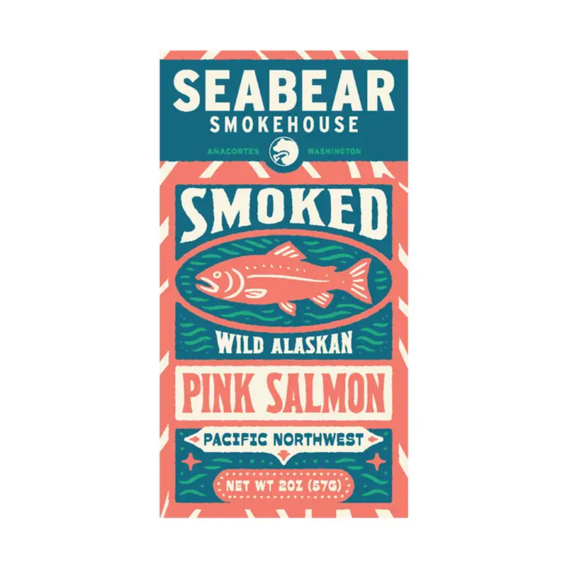 A rectangular package label or box front for Seabear Smokehouse smoked wild alaskan pink salmon, shown on a plain white background. The design uses teal, coral pink, cream, and dark blue with a fish illustration and the text 'Seabear Smokehouse,' 'Smoked,' 'Wild Alaskan,' and 'Pink Salmon.