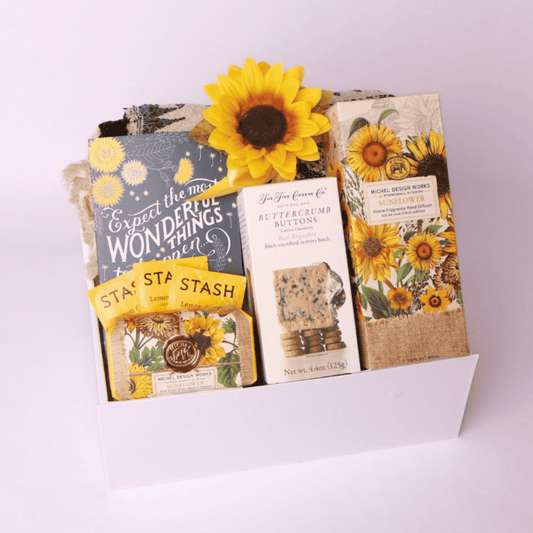 “Sunflower-themed gift box from a Seattle small business featuring cozy throw, tea, journal, soap, diffuser, and gourmet crackers—perfect for thoughtful gifting.”