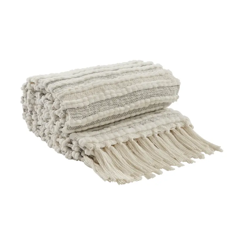 Textured throw blanket with pom-pom details on a white background