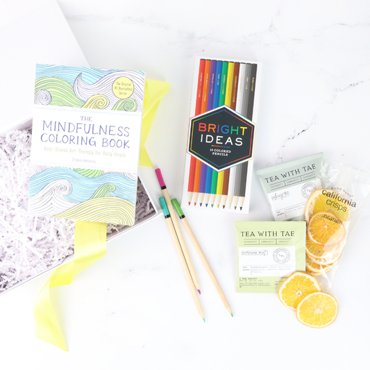 Thoughtful self-care gift featuring mindfulness coloring book, snacks, and creative tools arranged for gifting