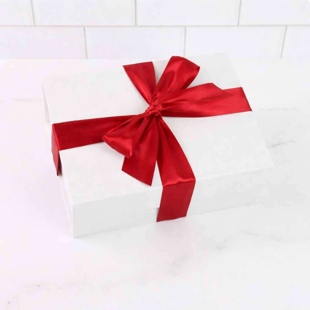 White gift box with a large red ribbon on a white tiled background