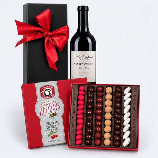 A holiday gift hamper featuring a bottle of Mark Ryan Winery Monkey Wrench Red Wine, a black gift box with a red bow, and a box of Chuck E. Cheese's Holiday Chocolate Cherries Nut & Hare Desserts, with the chocolate box open to show rows of red, brown, and white chocolates.